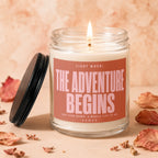 Candle with "The Adventure Begins" text for weddings, surrounded by dried leaves and petals.