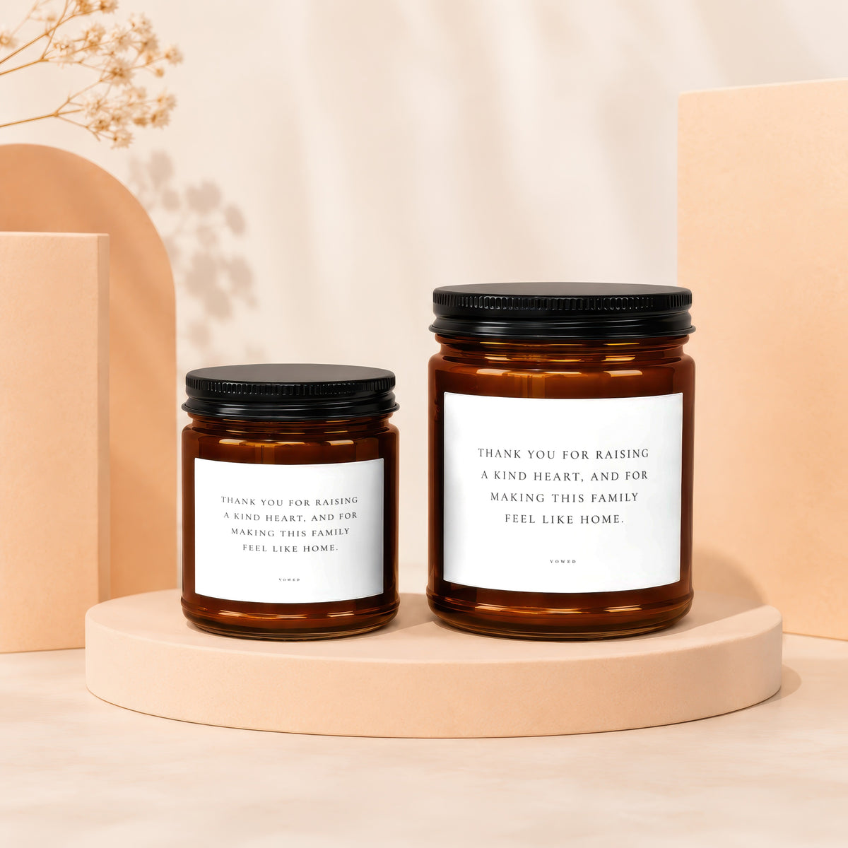Two amber glass candles with white labels reading "Thank you for raising a kind heart, and for making this family feel like home."