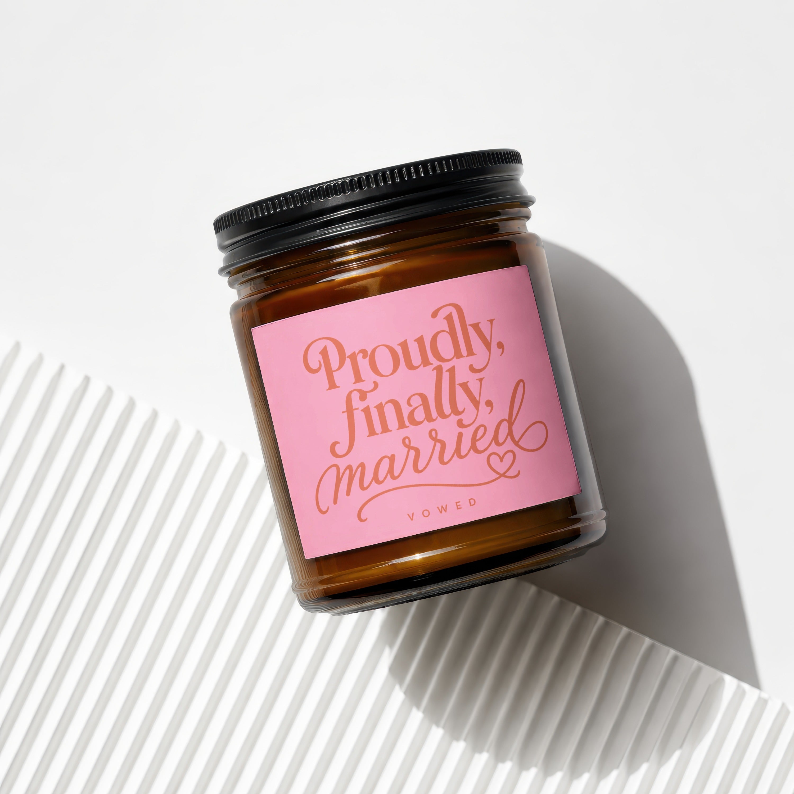 Amber glass candle with pink label reading "Proudly, finally, married" and "VOWED".