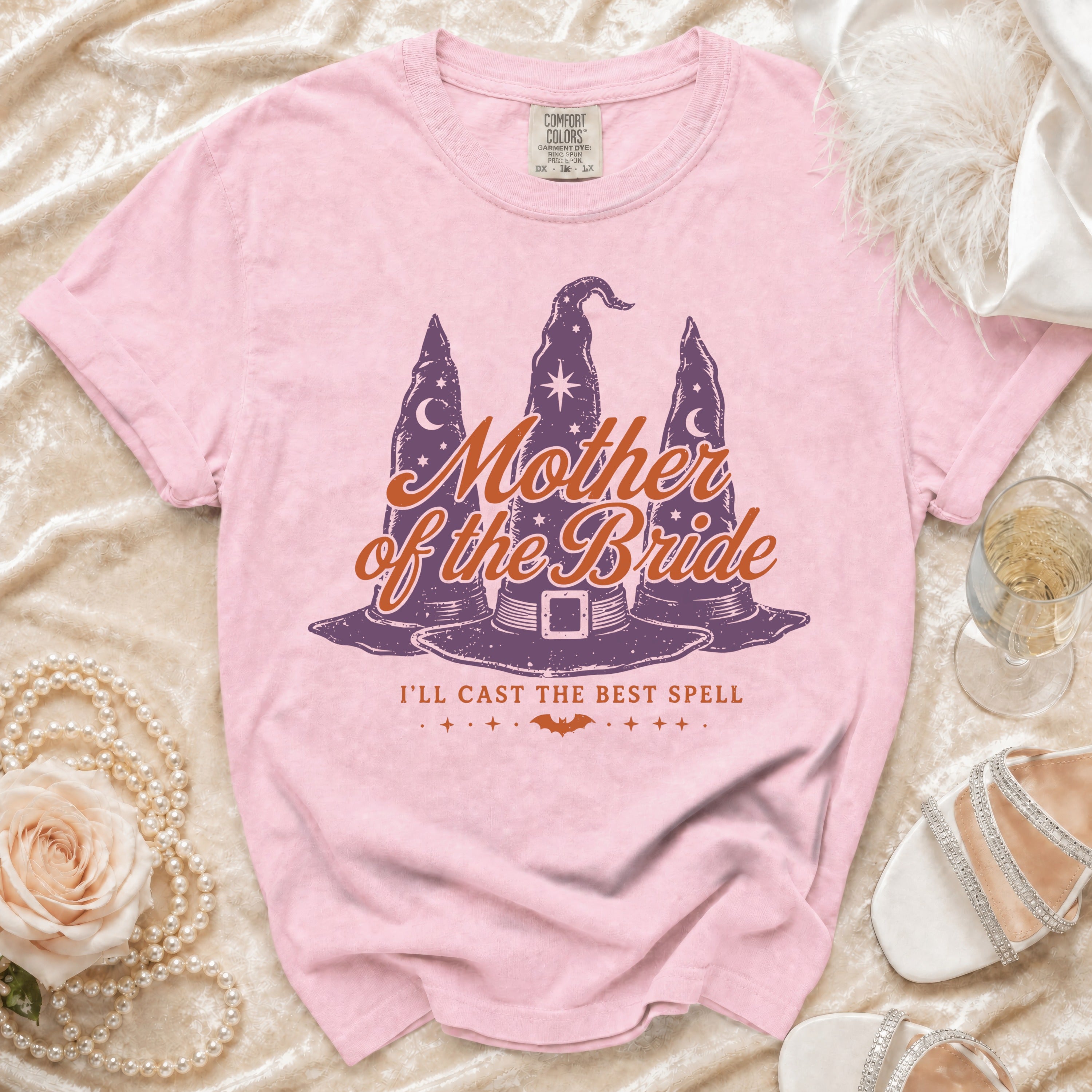 Pink t-shirt with "Mother of the Bride I'll Cast the Best Spell" text and witch hats.