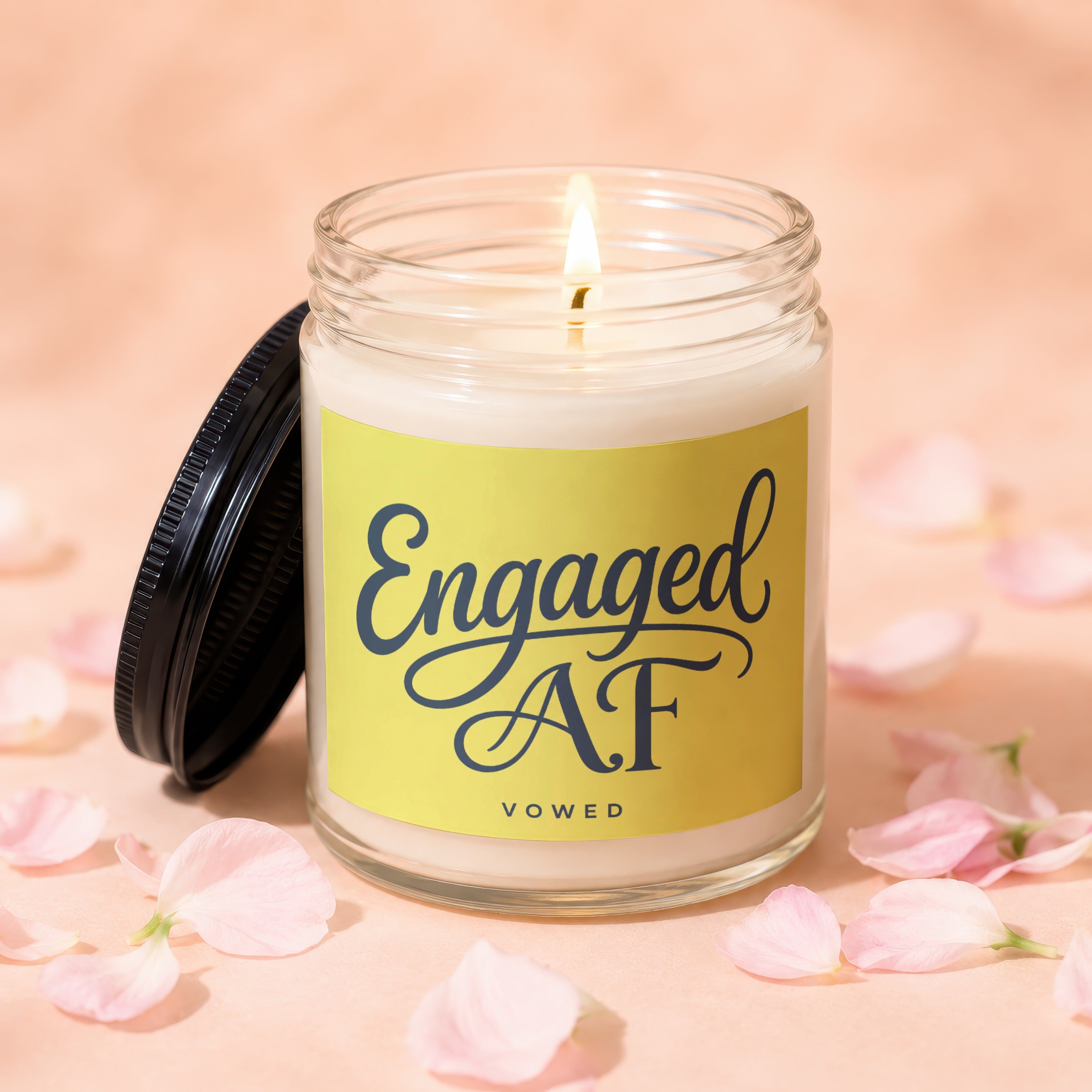 Candle with "Engaged AF" text on yellow label, surrounded by pink petals.