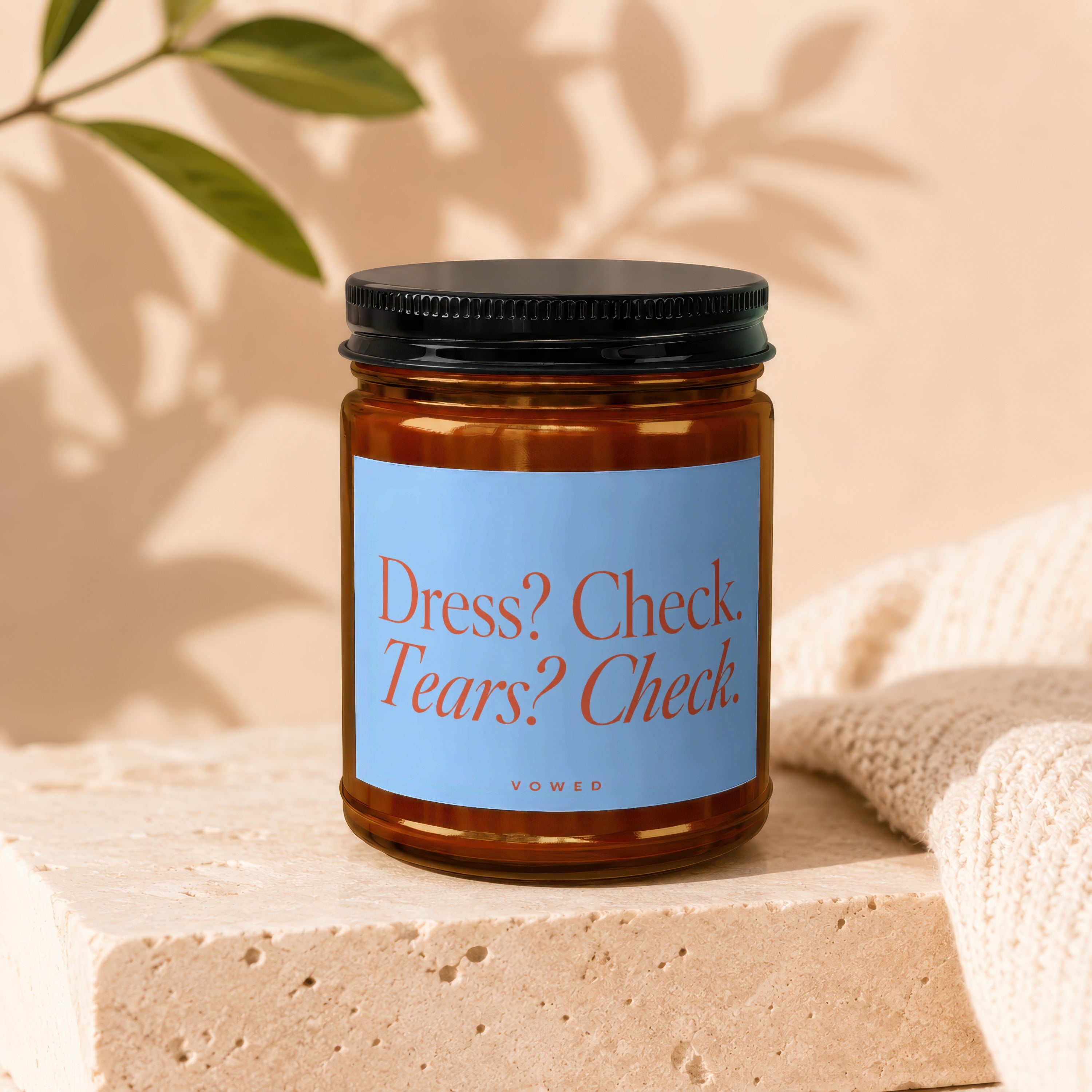 Amber jar candle with a light blue label that reads "Dress? Check. Tears? Check. VOWED."