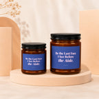 Two amber glass candles with blue labels reading "Be the Last Face I See Before the Aisle."