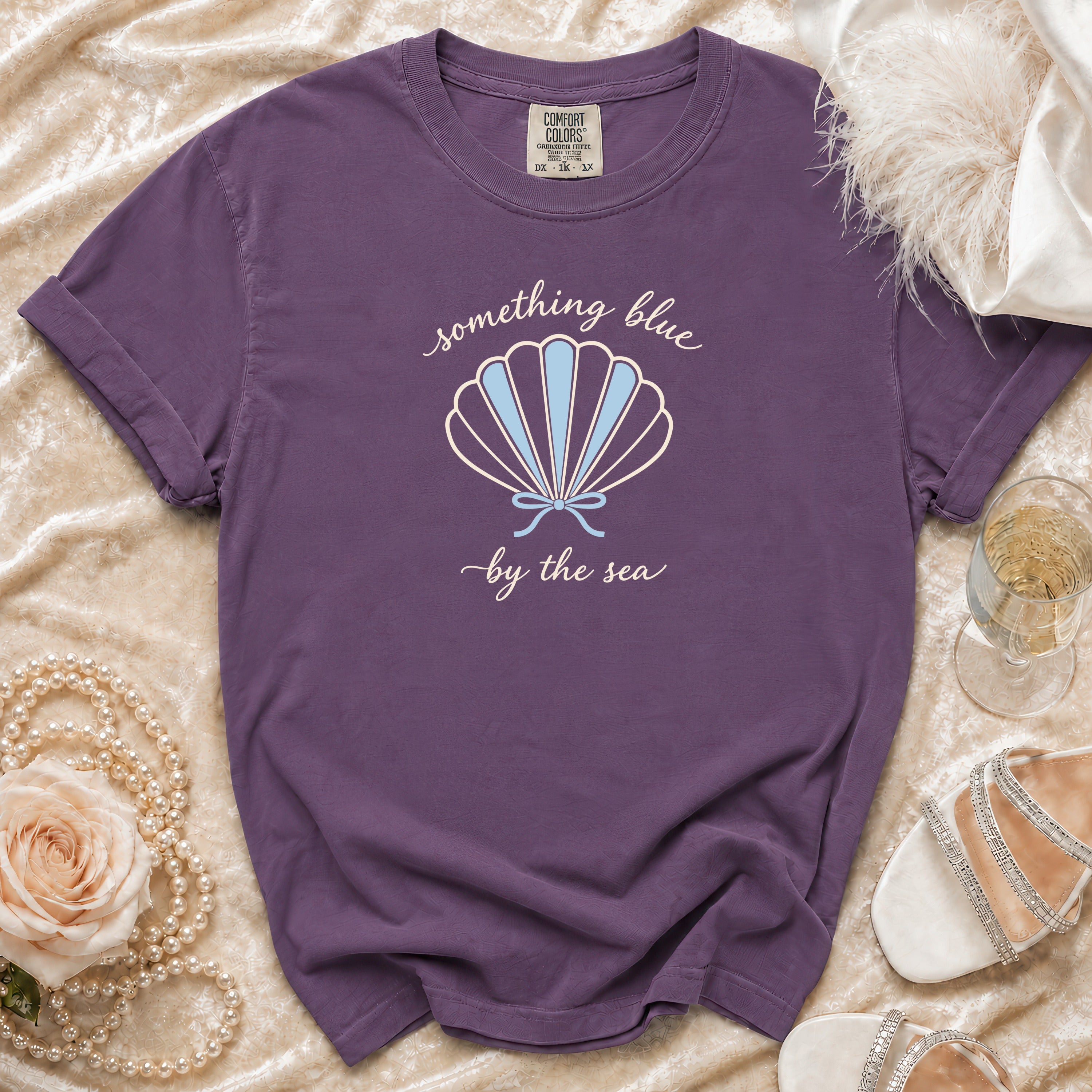 Purple t-shirt with "something blue by the sea" text and shell graphic.