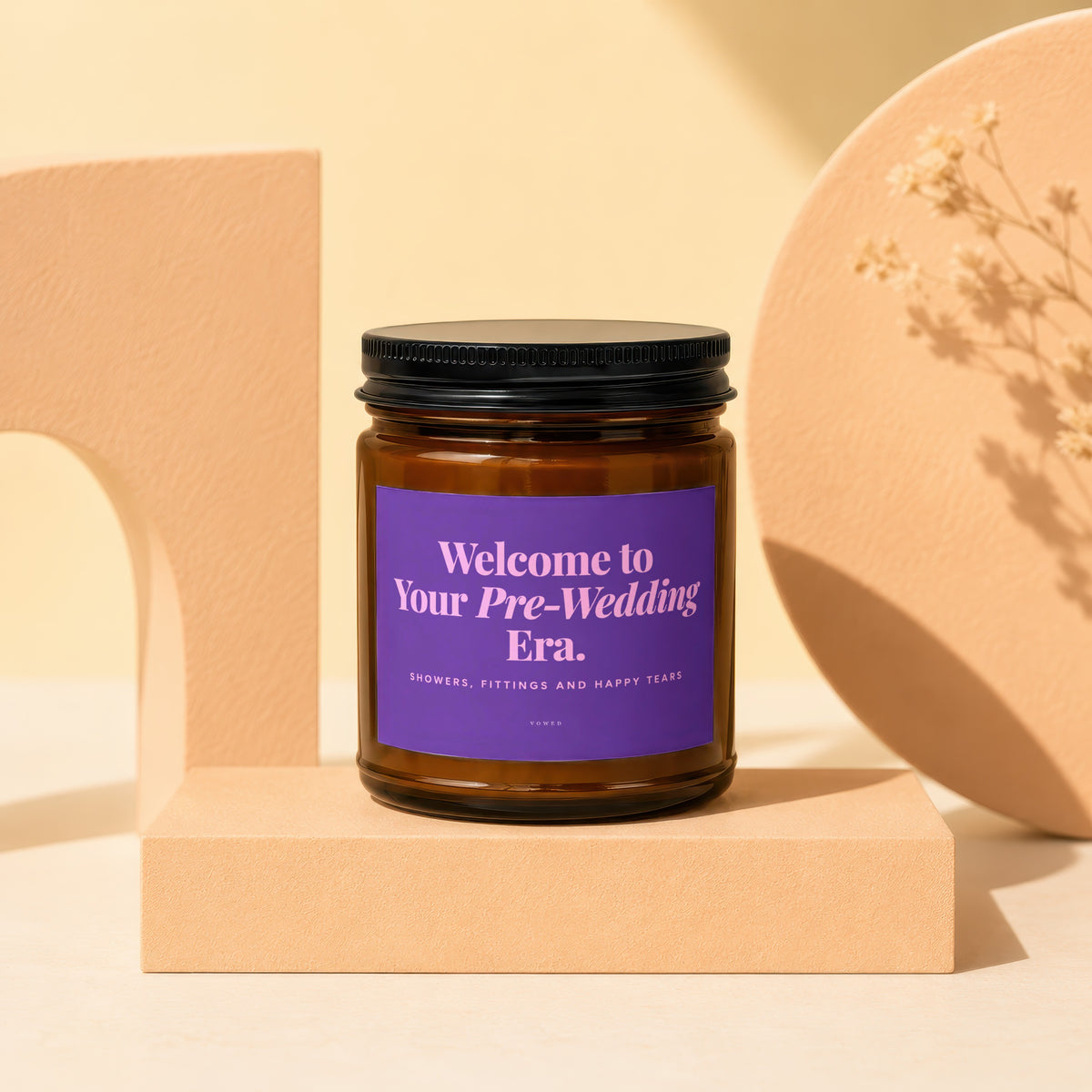 Amber glass candle with purple label reading "Welcome to Your Pre-Wedding Era."