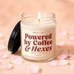 Lit candle in glass jar with black lid, reads "Smells like Powered by Coffee & Hexes."