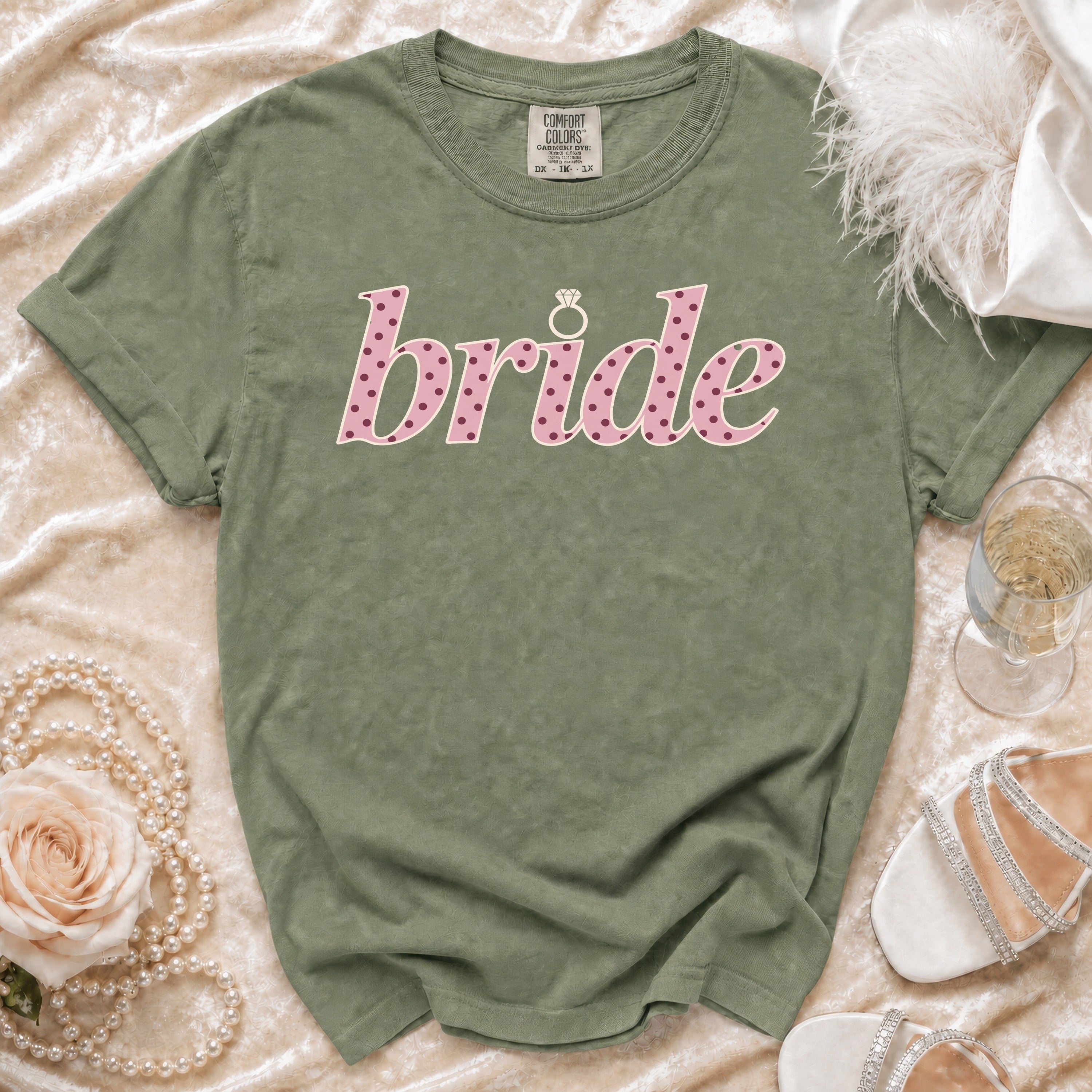 Olive green t-shirt with pink polka dot "bride" text and diamond ring graphic.