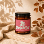Amber candle with pink label reading "The Odd Perfect Pair" and "vowed" below.