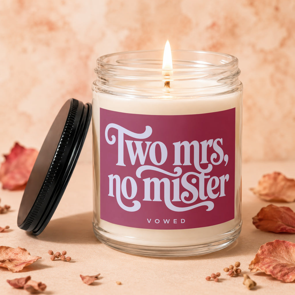Glass candle with burning wick and "Two mrs, no mister" text.