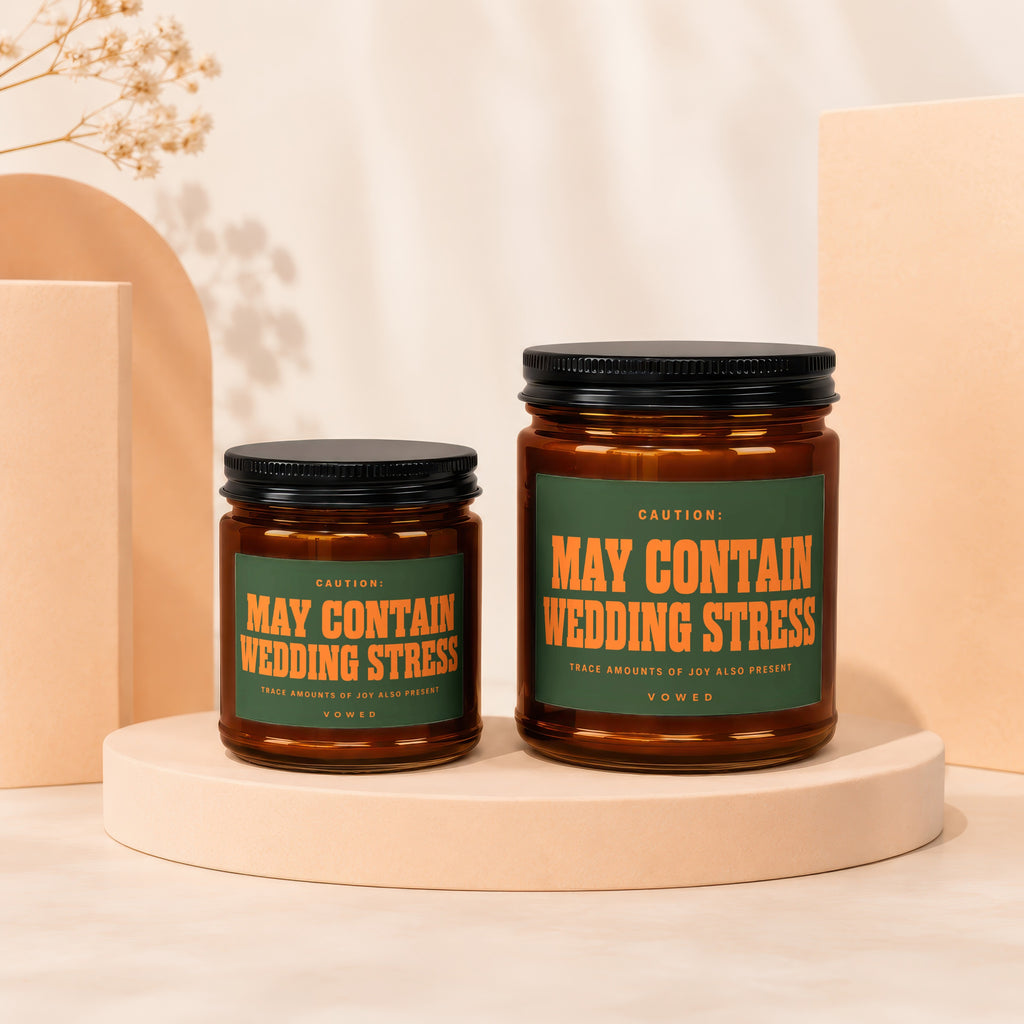 Two candles in amber jars with green labels reading "May Contain Wedding Stress".