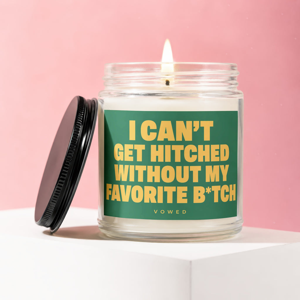 Glass candle with burning wick and black lid, featuring green label with yellow text.