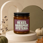 Amber jar with black lid, purple label reads "HEXES. HAIRSPRAY. HYSTERIA."