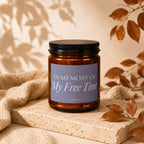Amber candle with "In Memory of My Free Time, Vowed" text on a purple label.