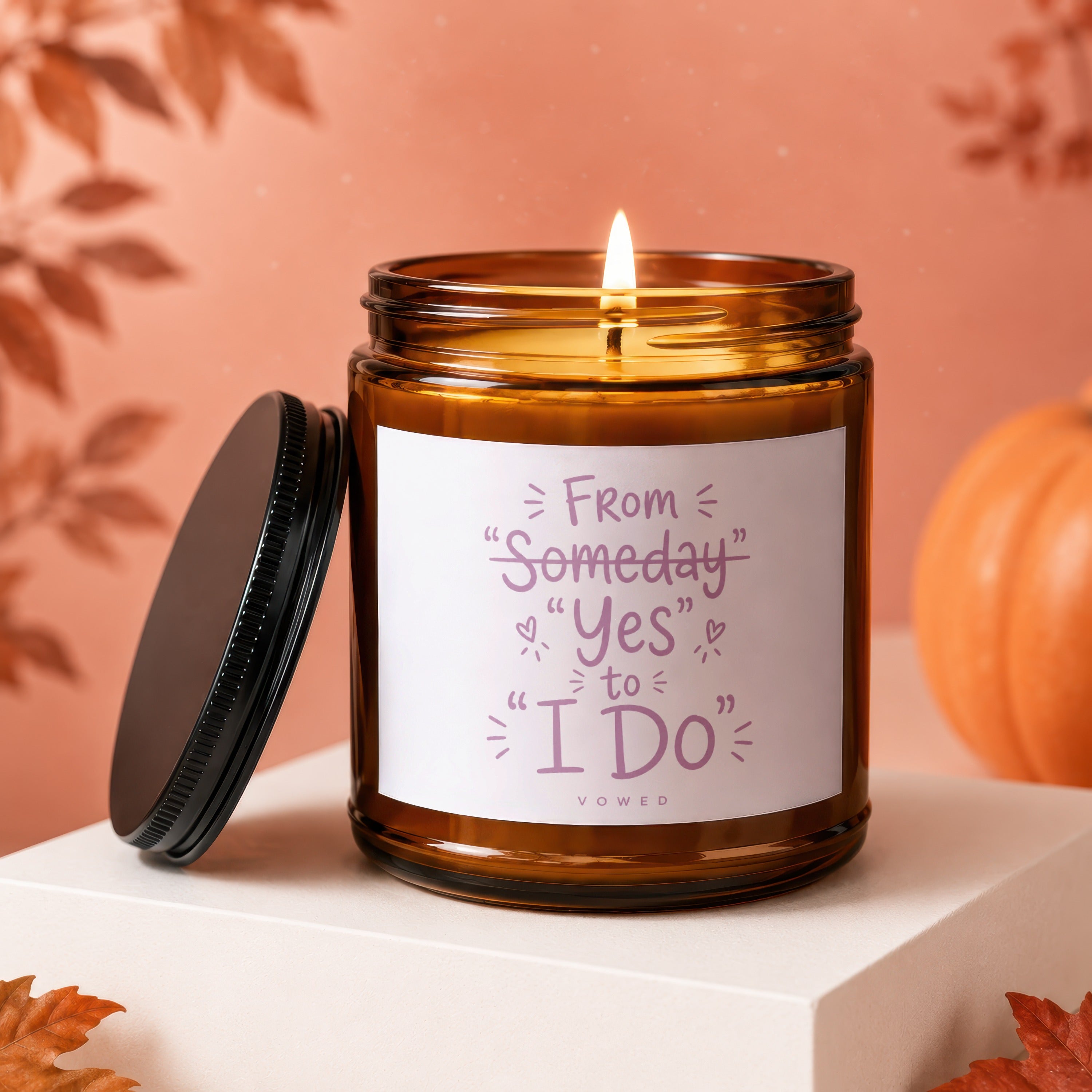 Amber candle with lit wick, featuring text "From Someday Yes to I Do" and "VOWED".