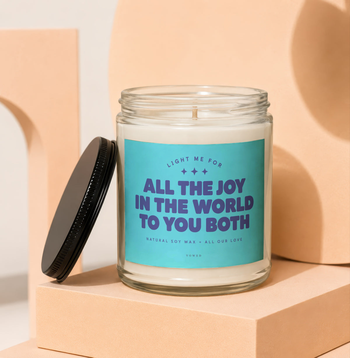 Soy wax candle with teal label reading "All the Joy in the World to You Both."