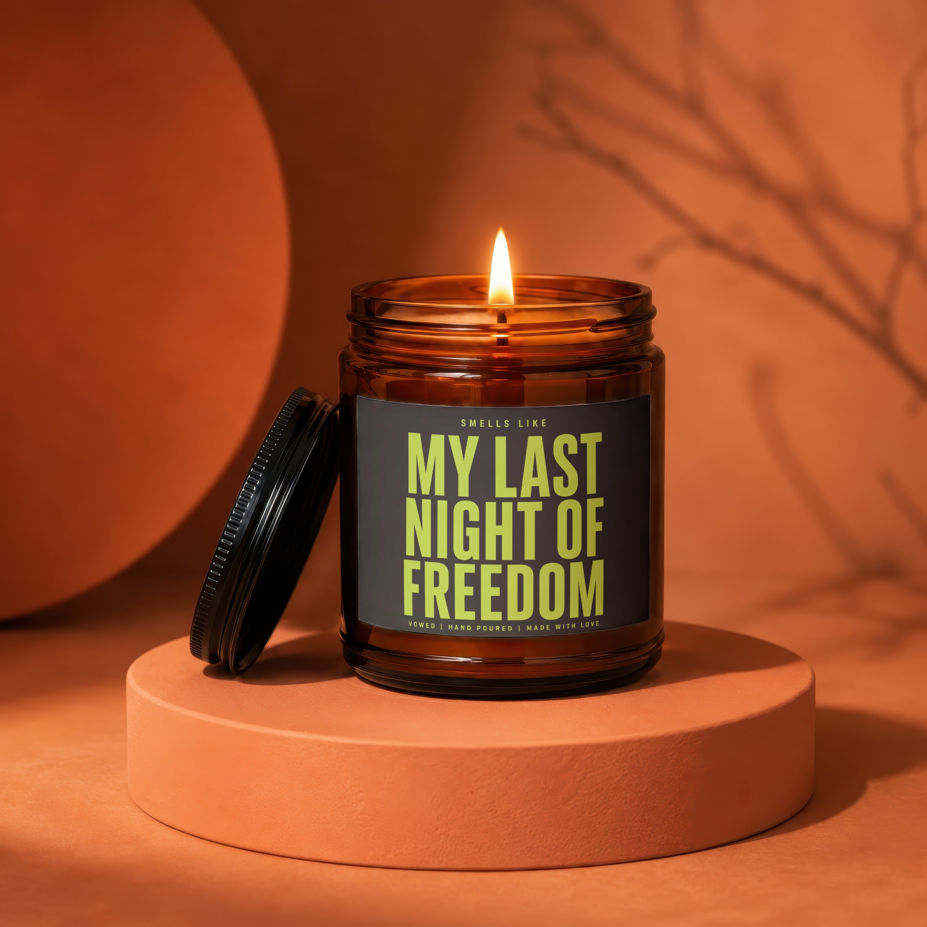 Amber jar candle labeled "My Last Night of Freedom" on orange pedestal.