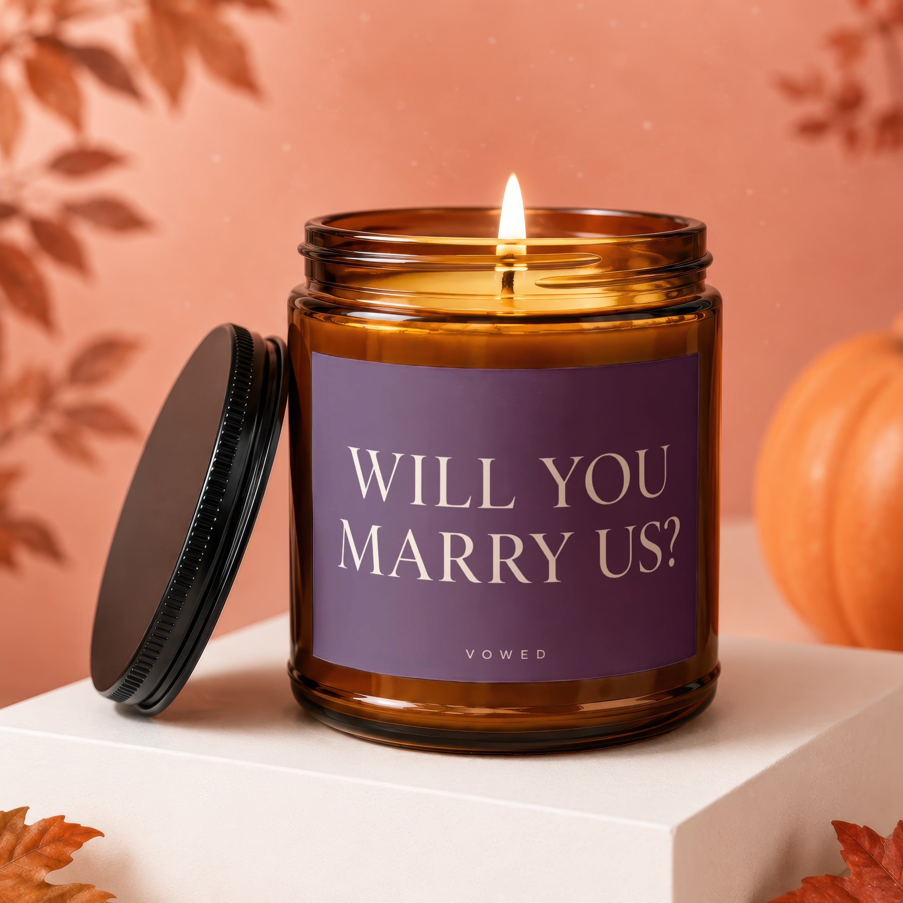 Lit amber jar candle with a purple label that reads "WILL YOU MARRY US? VOWED".