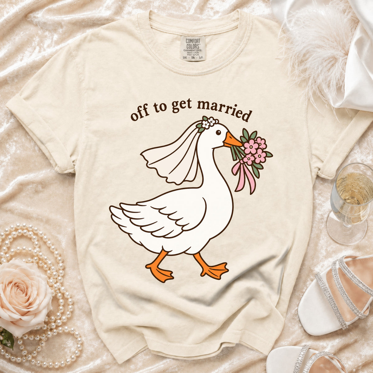 Cream t-shirt with a cartoon goose wearing a veil and holding flowers, text reads "off to get married".