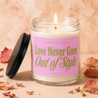 Lit candle in glass jar with pink label reading "Smells Like Love Never Goes Out of Style".