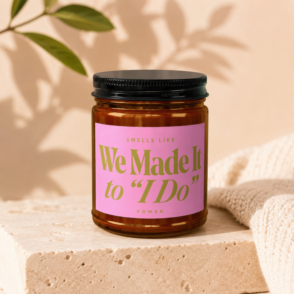 Candle with pink label that reads "Smells Like We Made It to 'I Do'" and "Vowed."