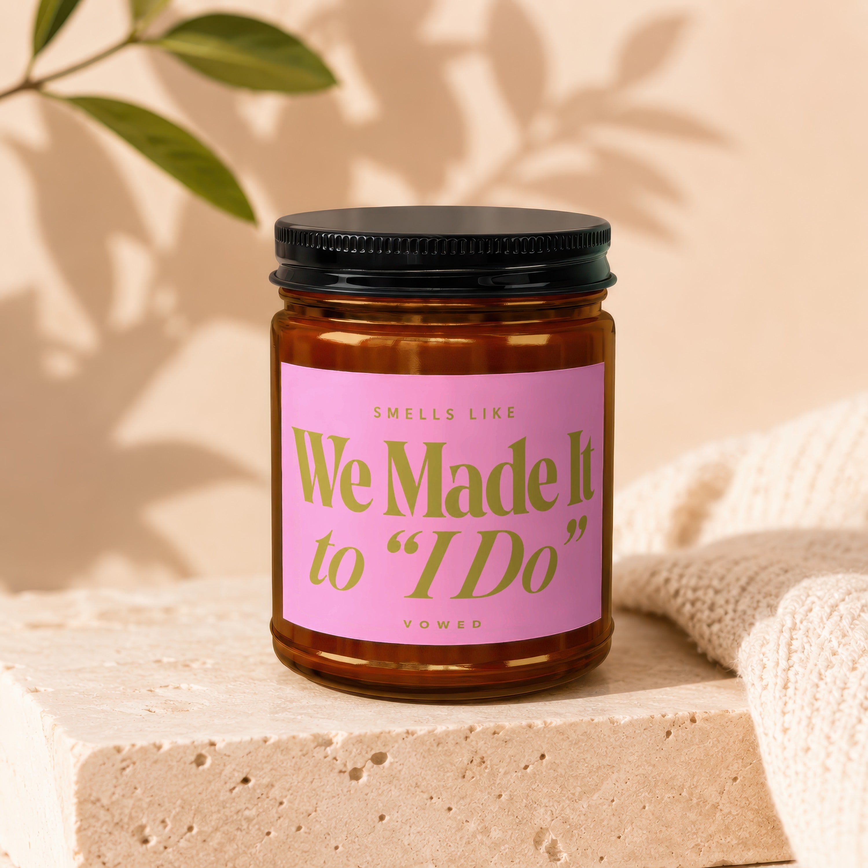 Candle with pink label that reads "Smells Like We Made It to 'I Do'" and "Vowed."