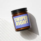 Amber jar candle with blue label reading "SWIPED RIGHT BEST DECISION EVER VOWED".