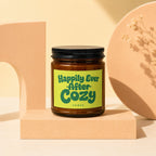 Amber jar candle with "Happily Ever After Cozy Vowed" text on a lime green label.