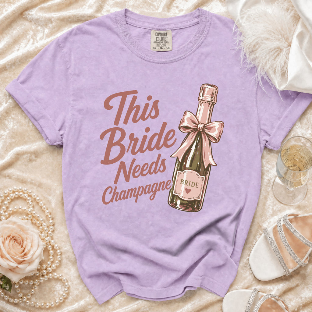 Purple t-shirt with "This Bride Needs Champagne" and champagne bottle graphic.