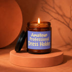 Amber candle jar with lit flame on an orange pedestal, with text "Amateur Professional Dress Holder".