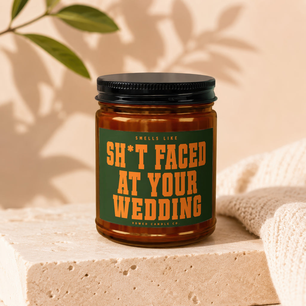 Amber candle with black lid, label reads "Smells Like Sh*t Faced At Your Wedding".