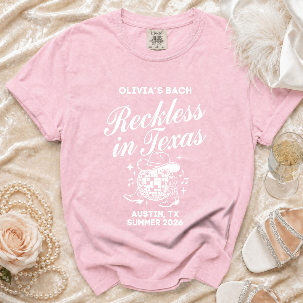 Pink t-shirt with "Olivia's Bach Reckless in Texas" in white text and graphics.