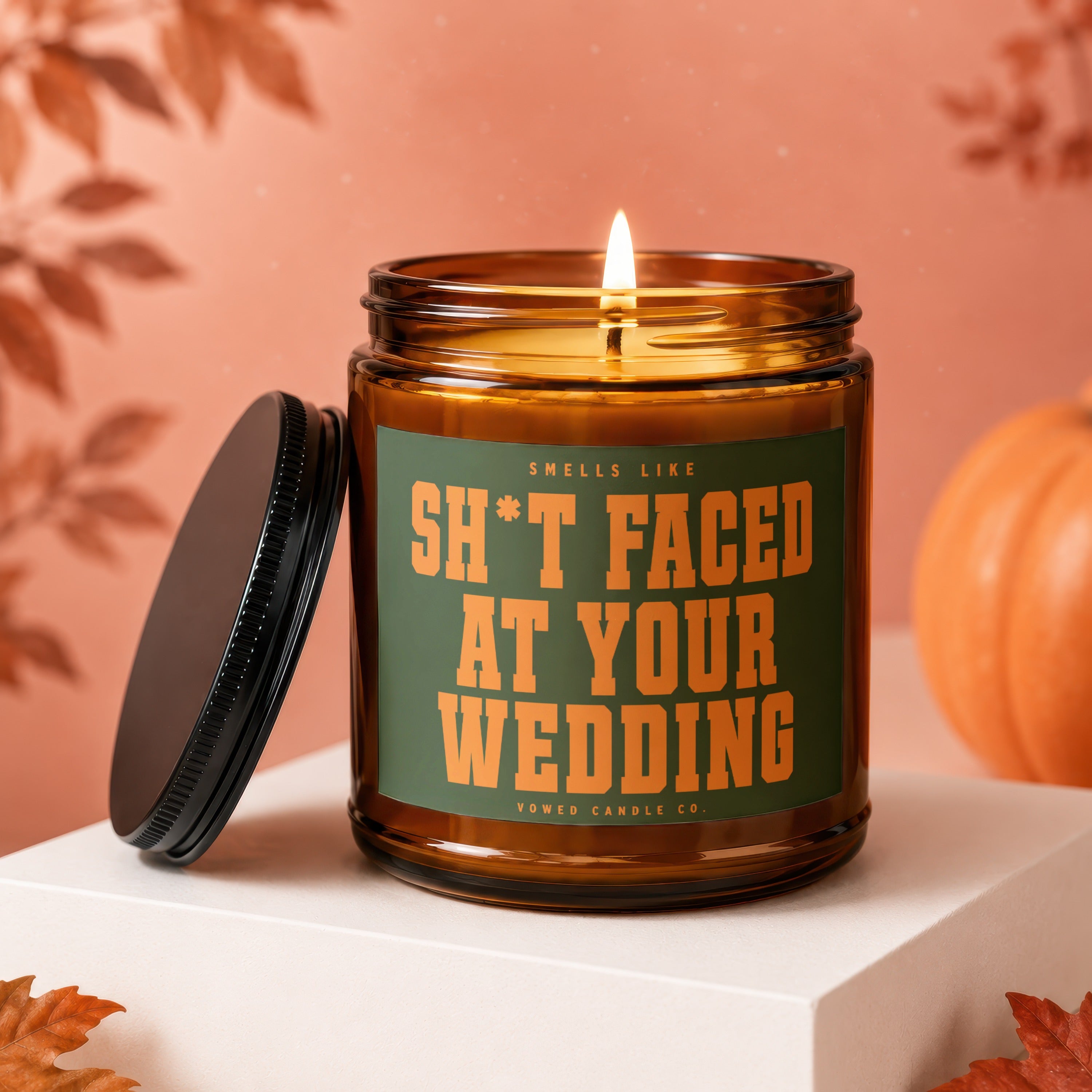Amber jar candle with "Sh*t Faced At Your Wedding" text, lid off.