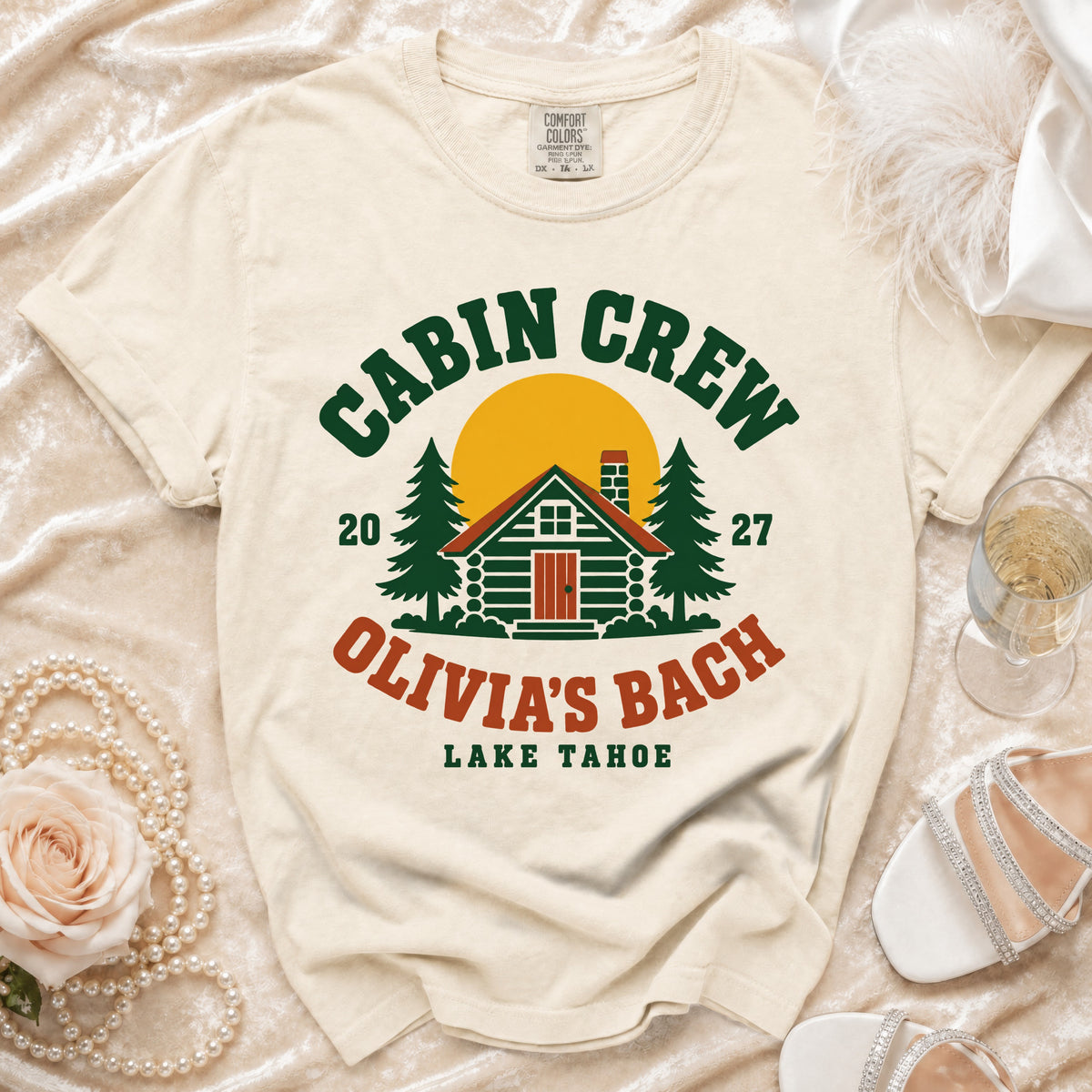 Cream t-shirt with "CABIN CREW," a cabin, trees, and "OLIVIA'S BACH LAKE TAHOE" text.