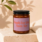 Brown glass candle with pink label reading "Happily Ever After Starts Now."