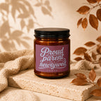 Amber candle with "Proud parent of a newlywed vowed" label on textured stone.