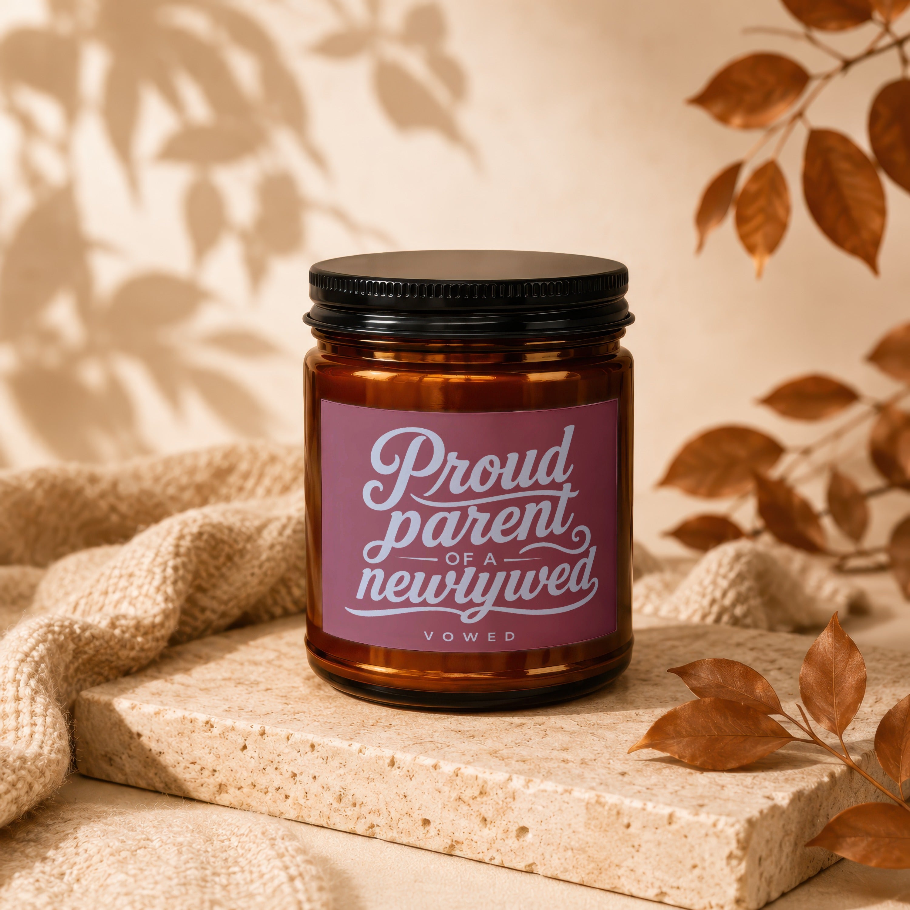 Amber candle with "Proud parent of a newlywed vowed" label on textured stone.
