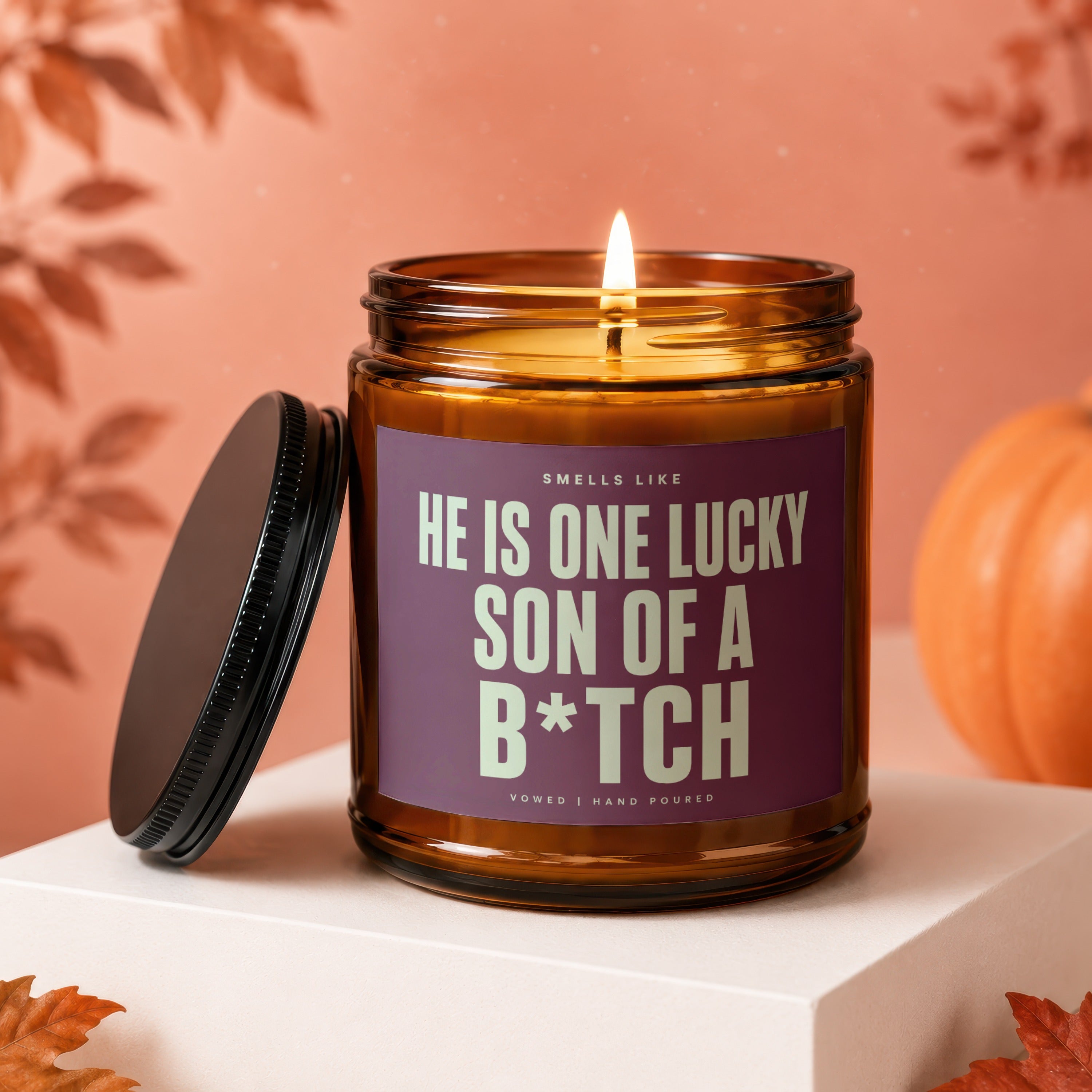 Amber jar candle with black lid and label reading "He is one lucky son of a B*tch."