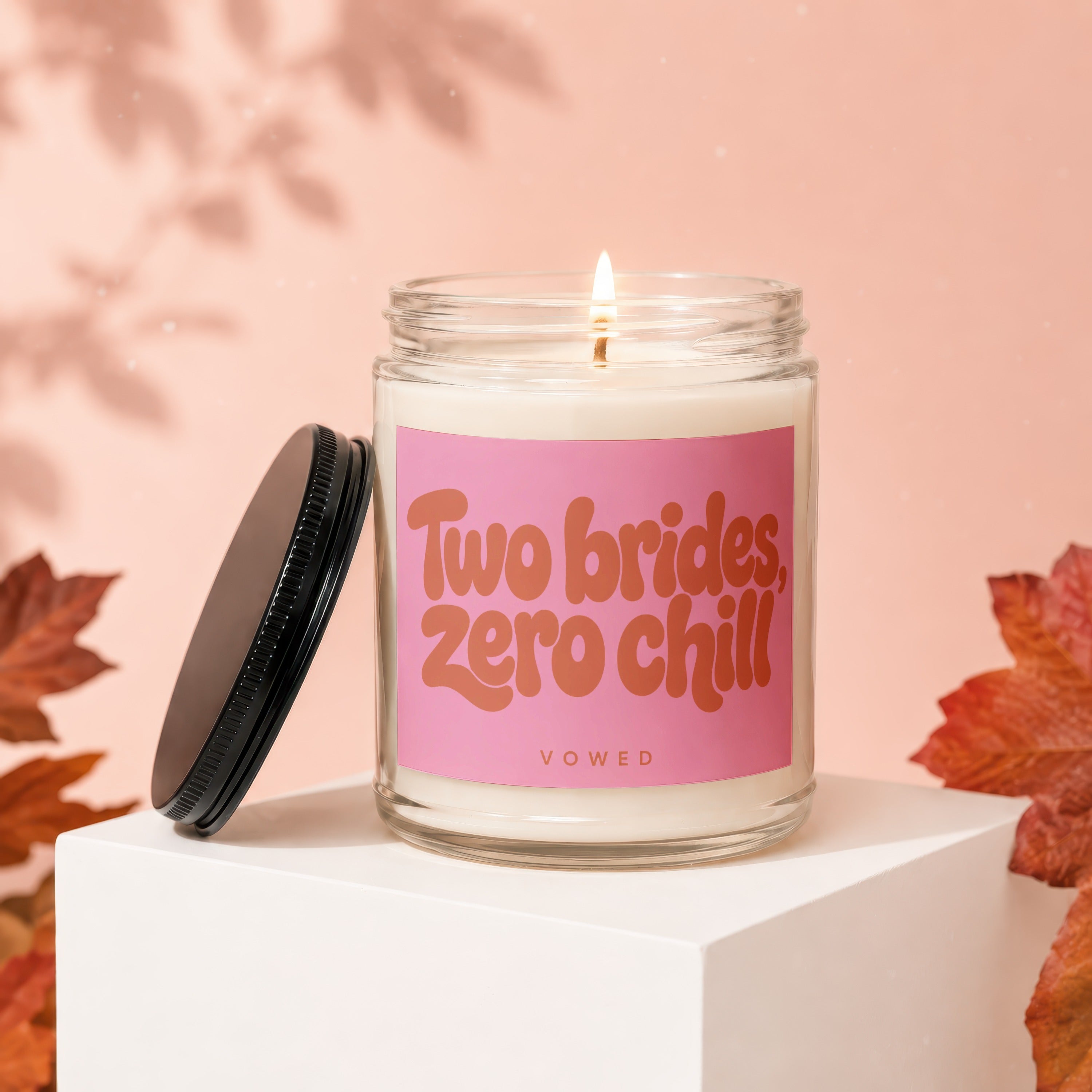 Glass candle with pink label that reads "Two brides, zero chill VOWED".