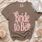 Brown t-shirt with pink "Bride to Be" text, ring, and floral design.