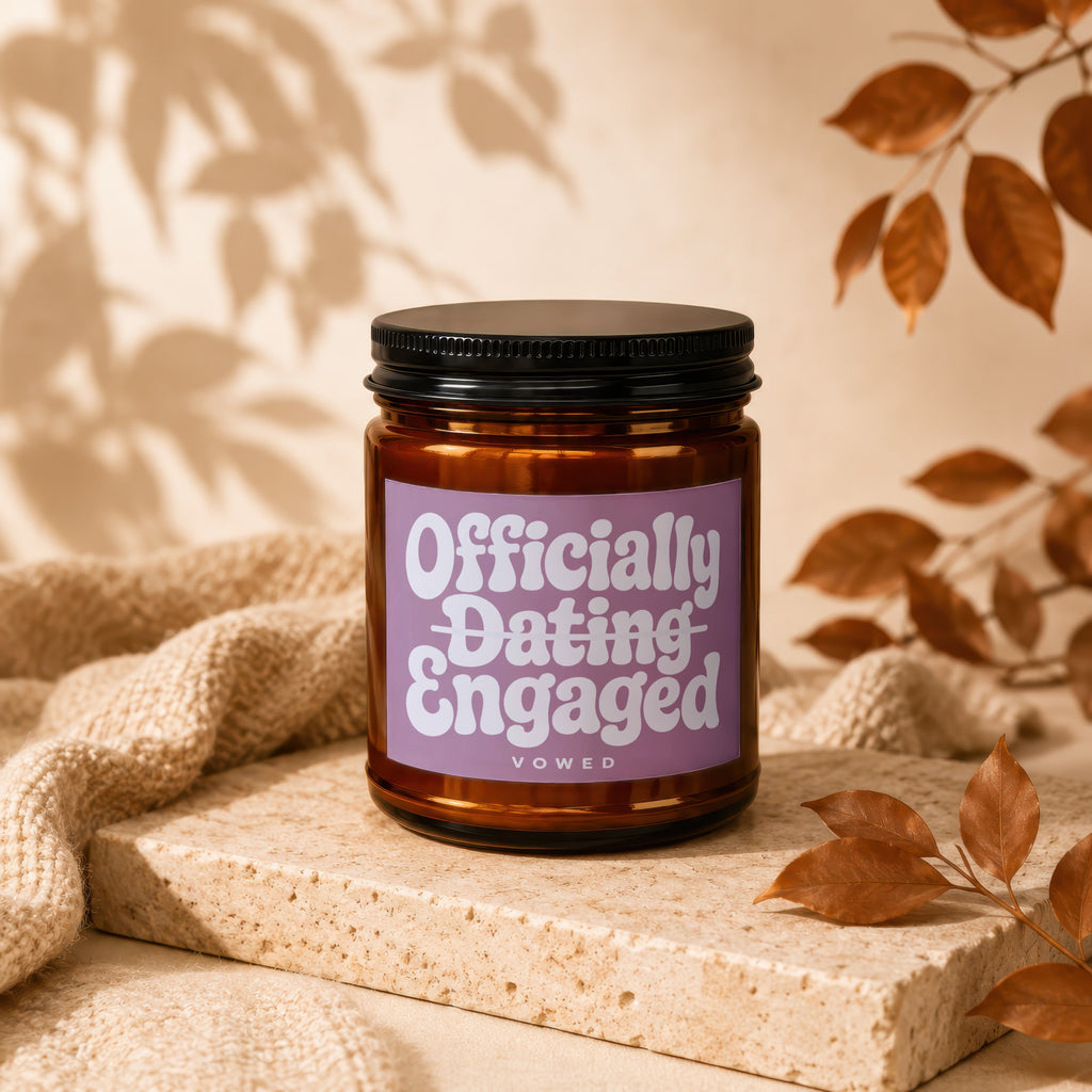 Candle with "Officially Dating Engaged" text on lavender label, with blanket and leaves.