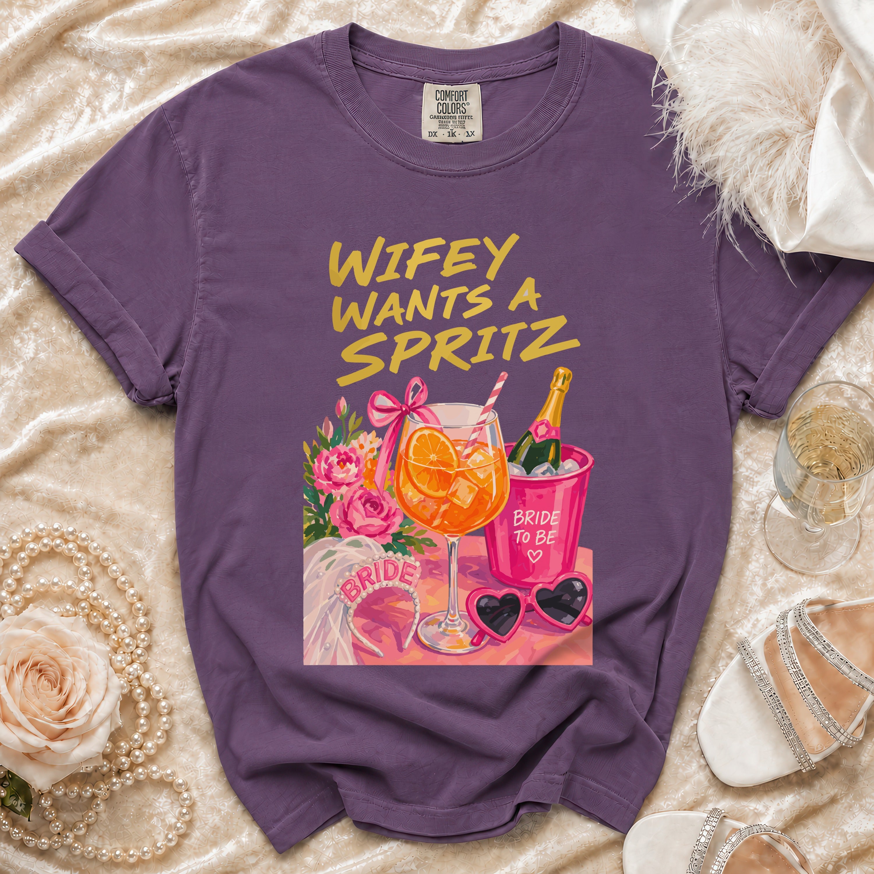 Purple t-shirt with "Wifey Wants A Spritz" graphic and bridal accessories.