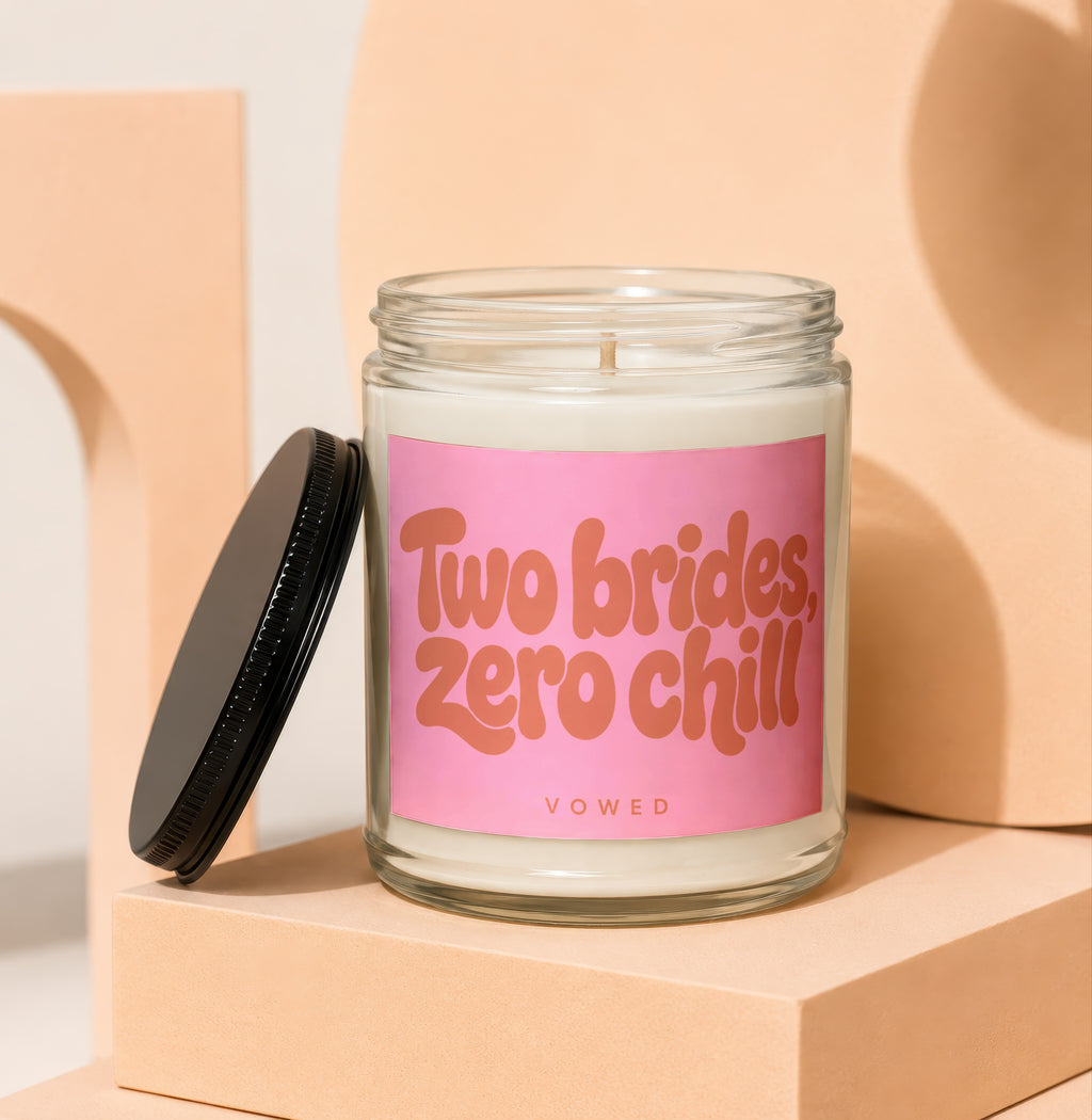 Glass jar candle with pink label reading "Two brides, zero chill".