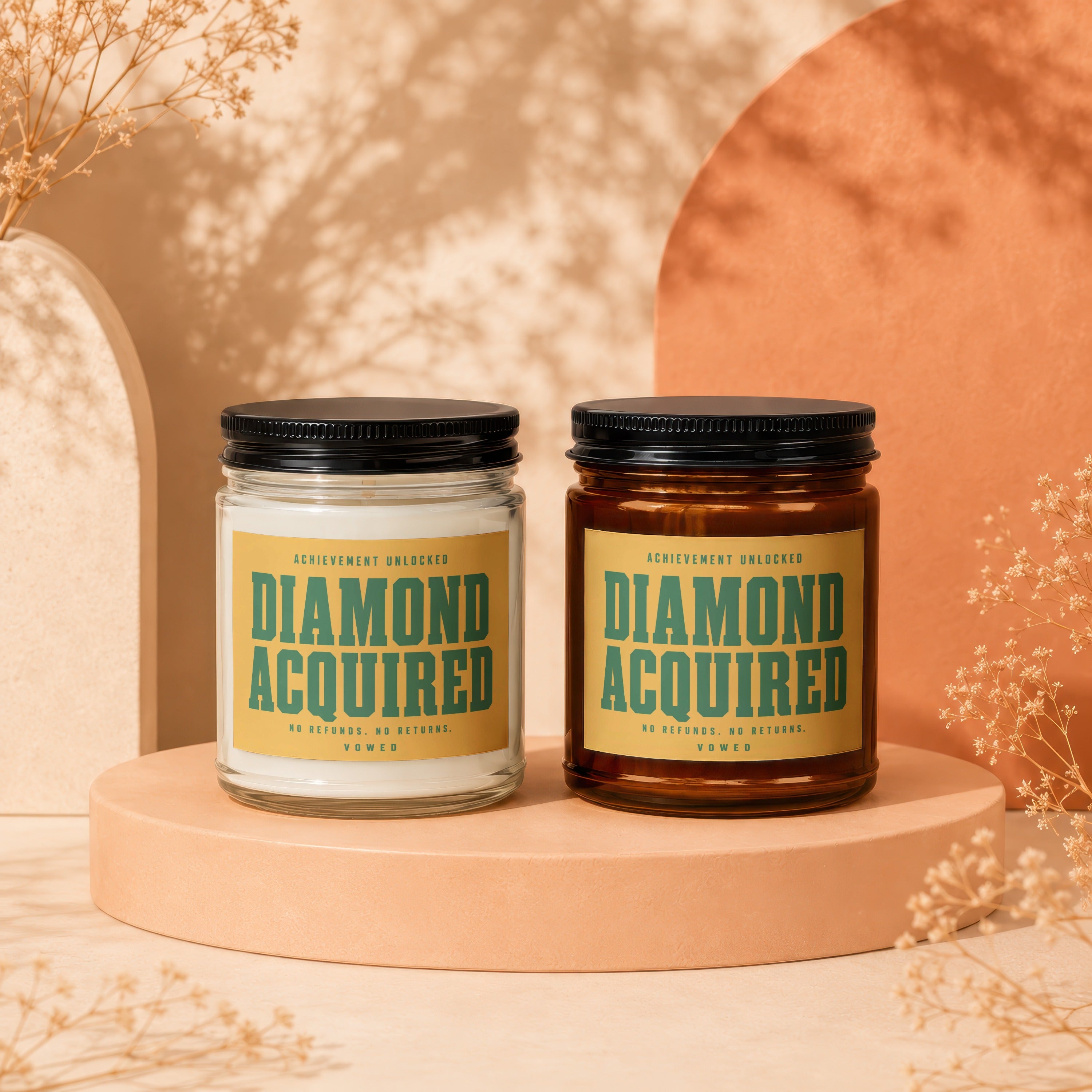 Two candles, white and amber, with labels reading "DIAMOND ACQUIRED".