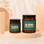 Two amber jars with black lids, one larger than the other, featuring dark green labels with white text.