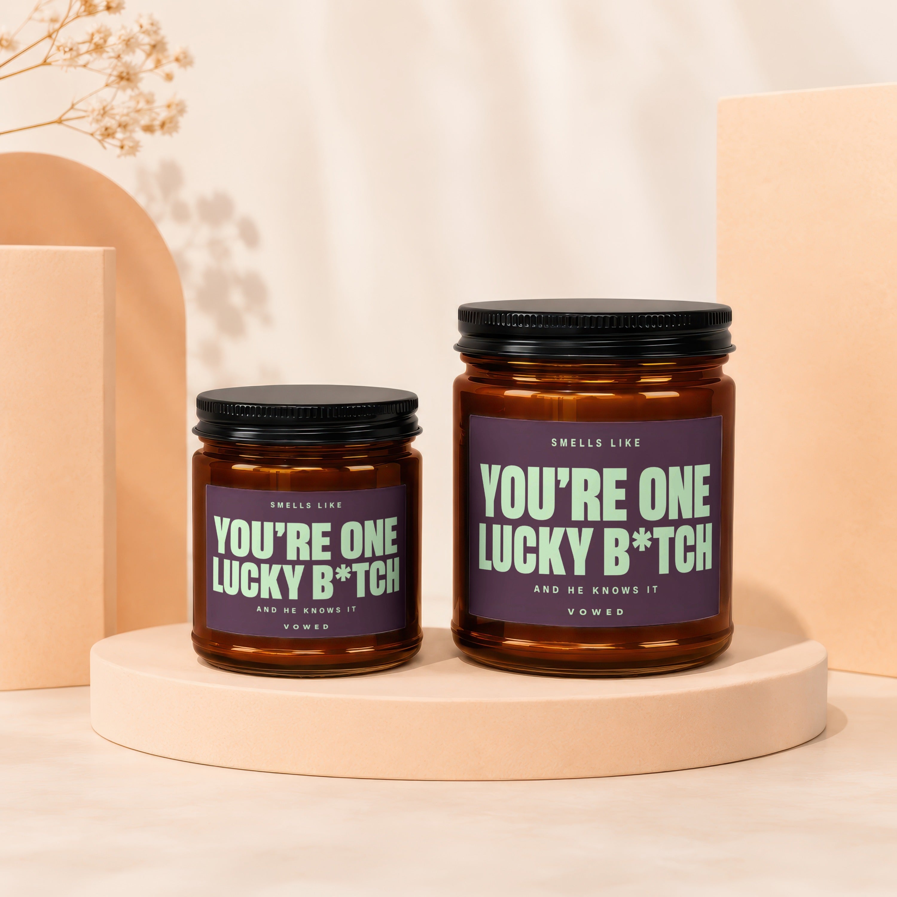 Two amber jar candles with black lids, labeled "YOU'RE ONE LUCKY B*TCH".