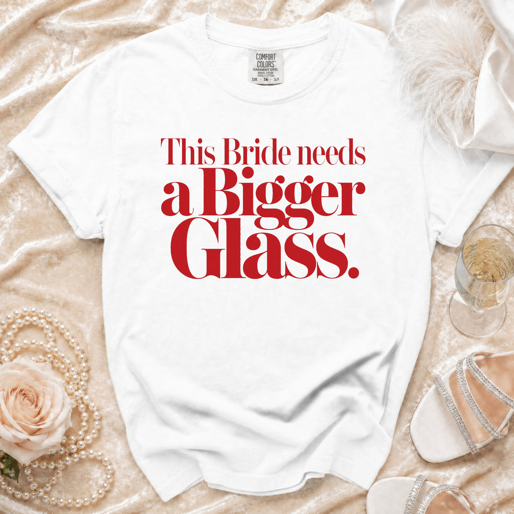 White t-shirt with red text "This Bride needs a Bigger Glass."