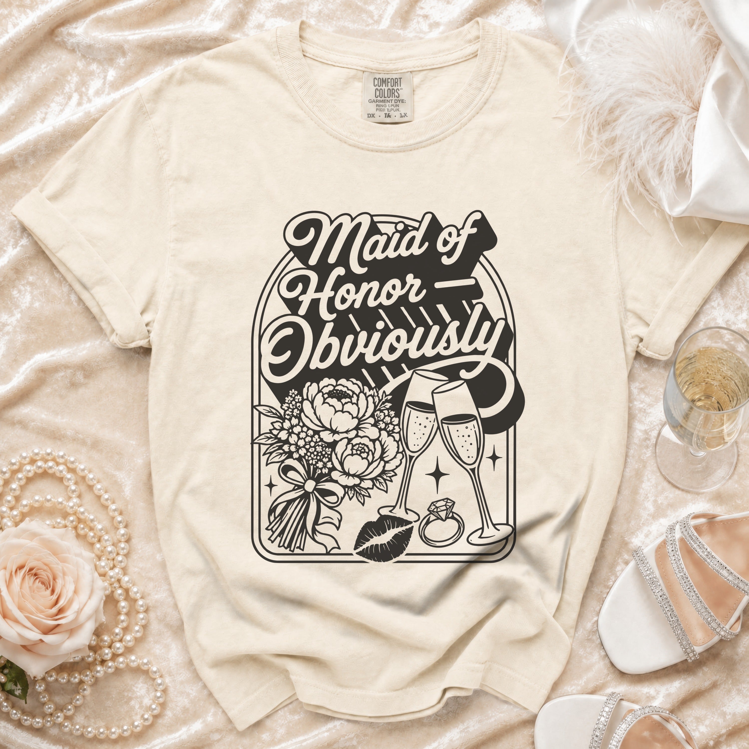 Light cream t-shirt with "Maid of Honor Obviously" graphic, flowers, rings, and glasses.