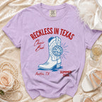 Purple t-shirt with "Reckless in Texas" and cowboy boot graphic.