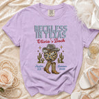 Lavender t-shirt with "Reckless in Texas" and "Olivia's Bach" design.