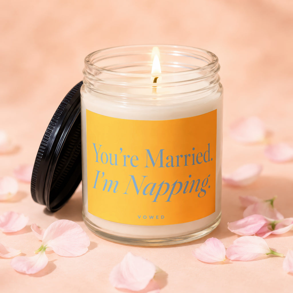 Jar candle with a lit wick and a yellow label reading "You're Married. I'm Napping."